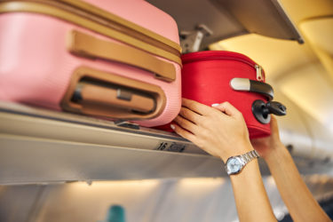 Person putting carry-on luggage in overhead bin