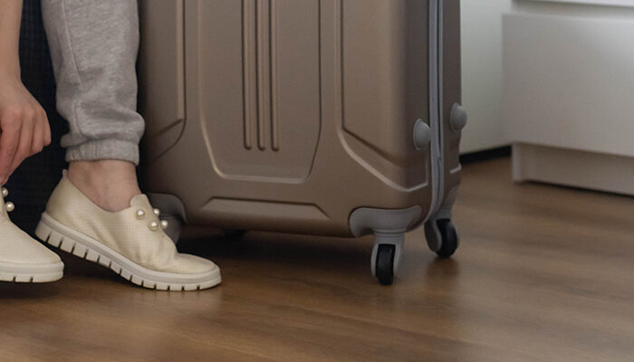 Close up of person putting on shoes next to rolling luggage