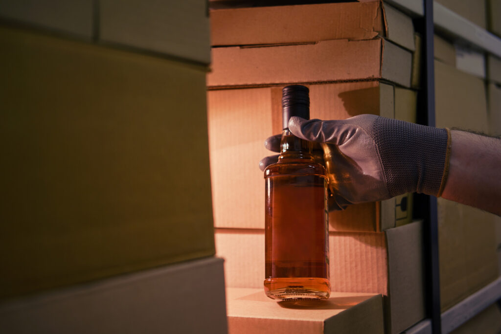 man holding liquor bottle in spirits warehouse ready for shipment